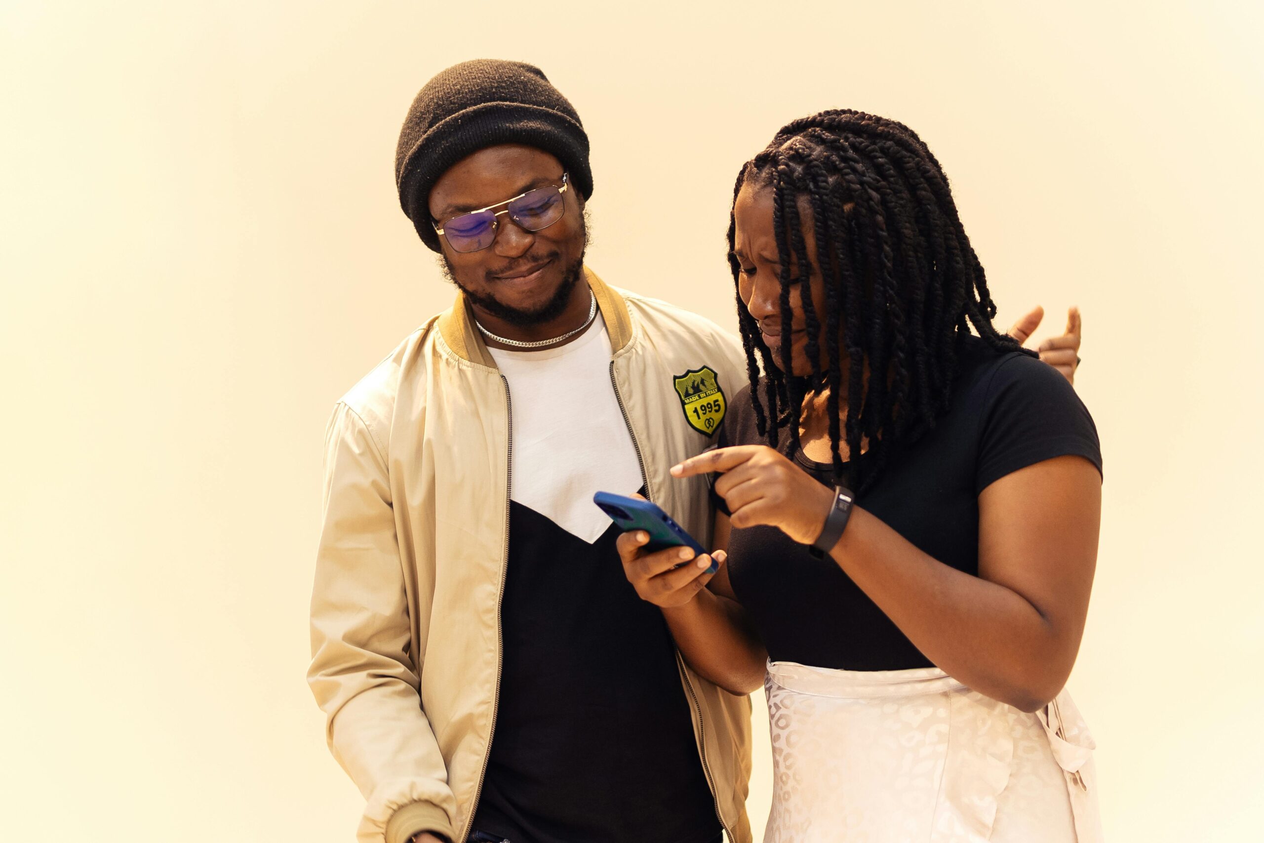 A man and woman smiling as they look at a smartphone outdoors in Lagos, Nigeria.